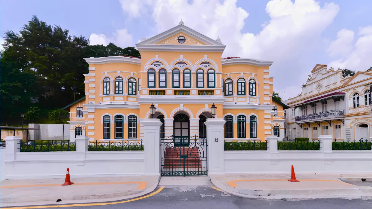 Rumah Tangsi Historic pastel-yellow colonial-style building behind a white fence and gate