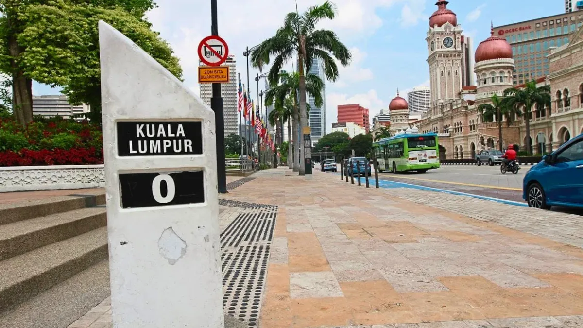 Zero Mile Marker Kuala Lumpur marker with city street, palm trees, and historic buildings in the background